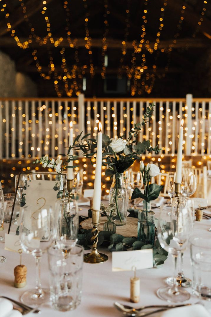 Neutral and sage green wedding tablescape with long candles and green foliage decorations