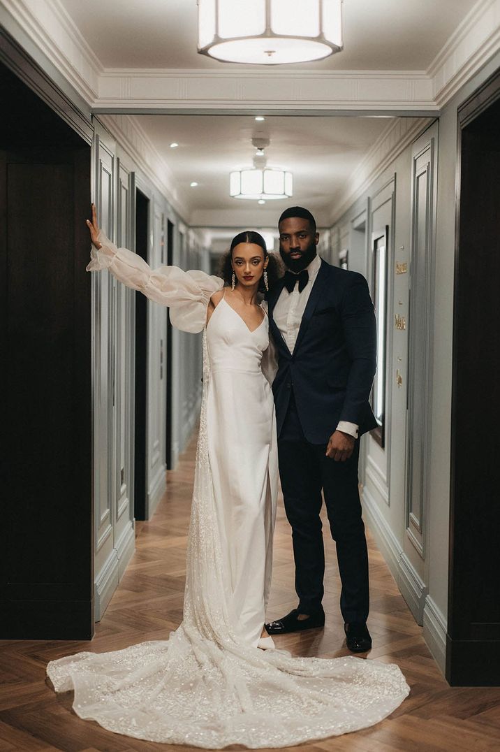 Bride in chic wedding dress with detachable sleeves and sparkly veil with the groom in black tie for Mayfair wedding in London