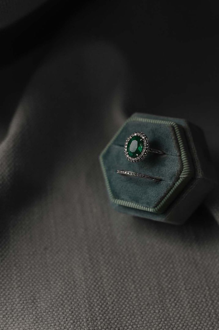 Oval emerald halo engagement ring and diamond wedding band in green velvet ring box 