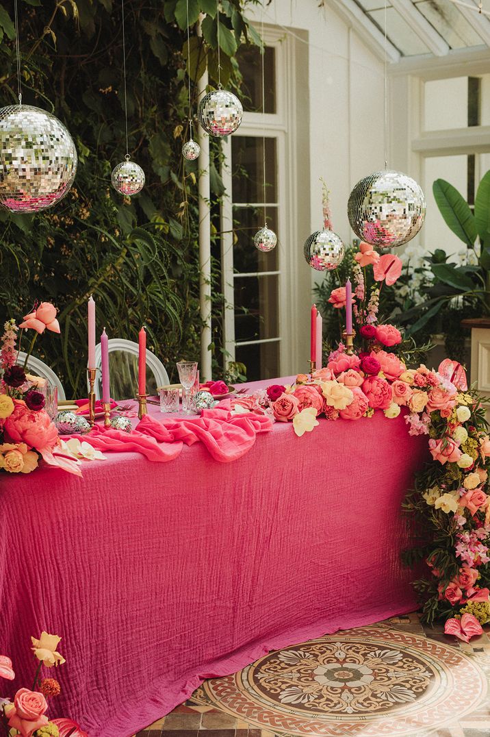 Hot pink table cloth on sweetheart table Valentine's Day wedding idea with disco balls and waterfall flowers 