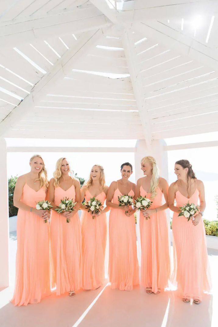 Bridesmaids standing in a row wearing maxi peach bridesmaid dresses