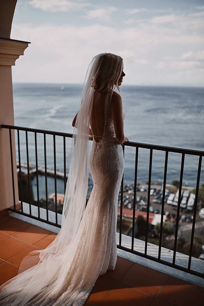 Bride wearing a beautiful beach wedding dress overlooking the sea on a balcony 