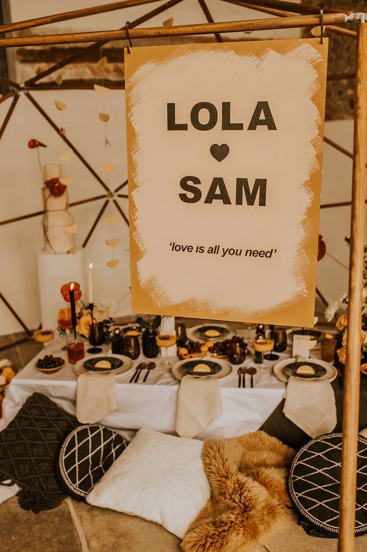 Yellow and white wedding welcome sign with the couple's name and a song lyric quote 