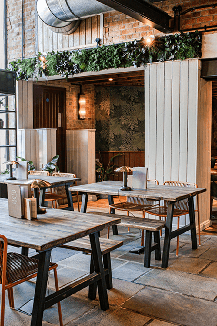 Wooden tables with orange chairs and benches for seating at The Hub on Verulam wedding venue 