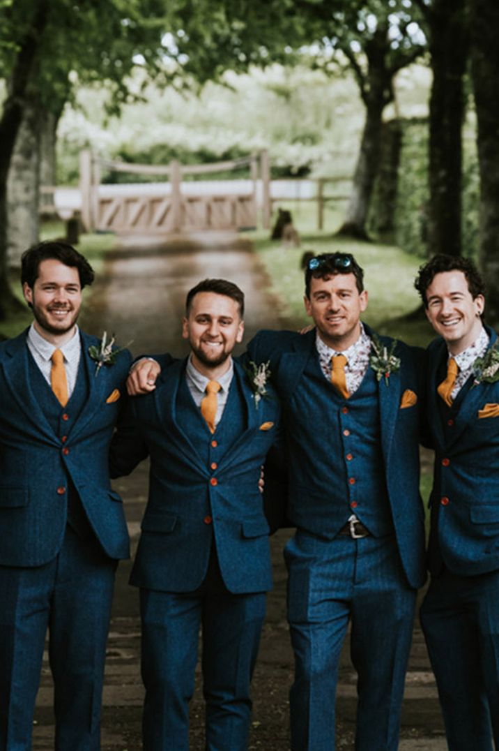 Groom and groomsmen wearing matching blue wedding suits with yellow tie 