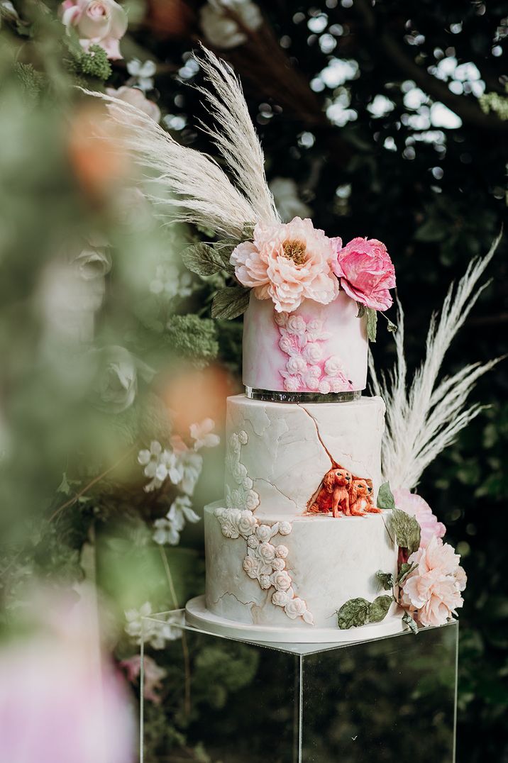 Three star white iced wedding cake with marble effect and pastel coloured flowers 