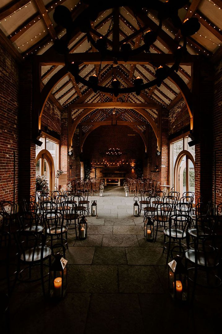 Magical, rustic and cosy winter wedding ceremony room with candles in lanterns and foliage for decoration 