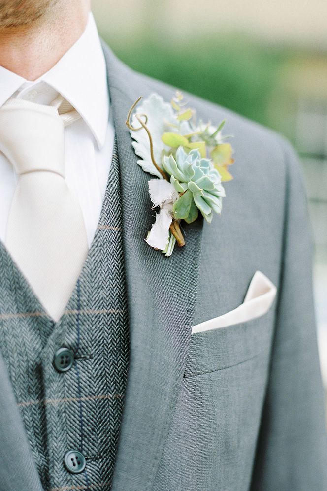 Groom in a light grey suit with foliage and succulent buttonhole 