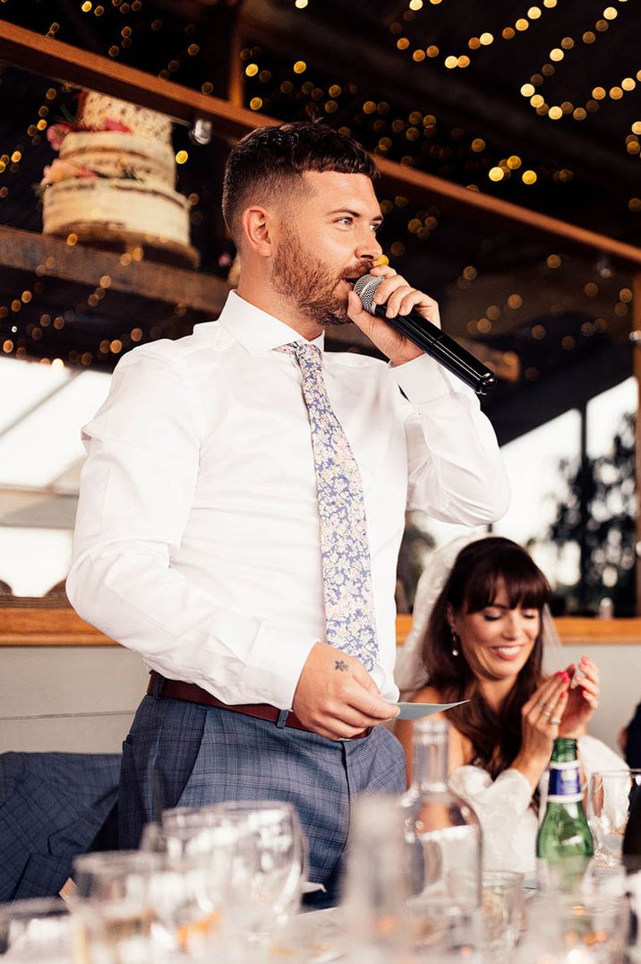 Groom in a white shirt and floral tie giving his groom speech