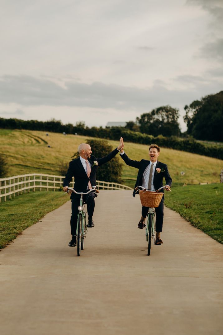 Couple share high five on bicycles at wedding