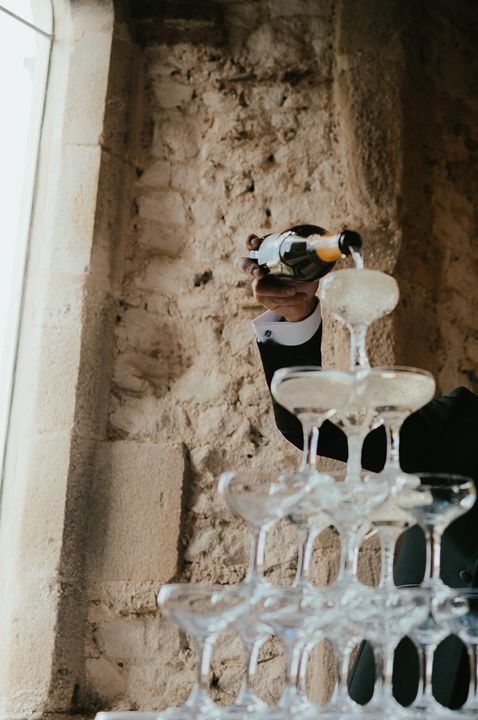 Bride in bandeau sparkly wedding dress and groom in black tux doing their wedding champagne tower 