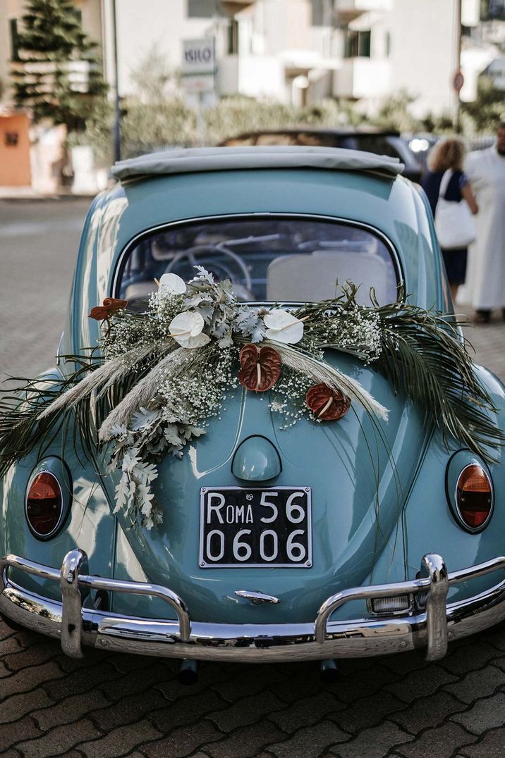 Aqua blue vintage wedding car with large floral decoration on boot