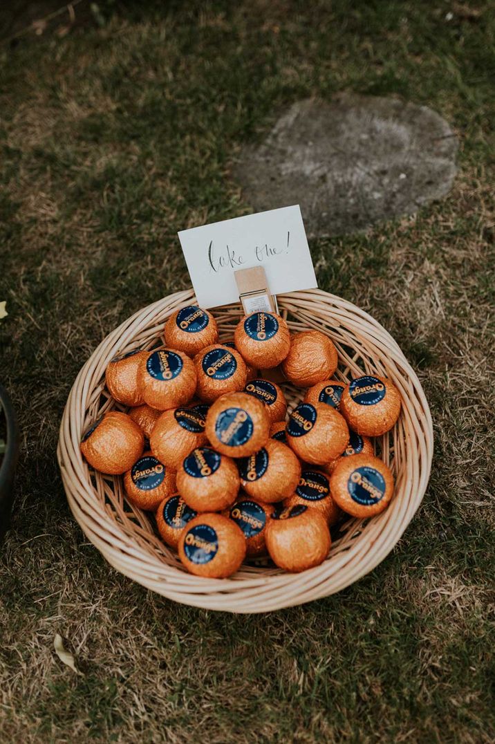 DIY wedding treats - chocolate oranges in a wicker basket with DIY sign saying take me attached