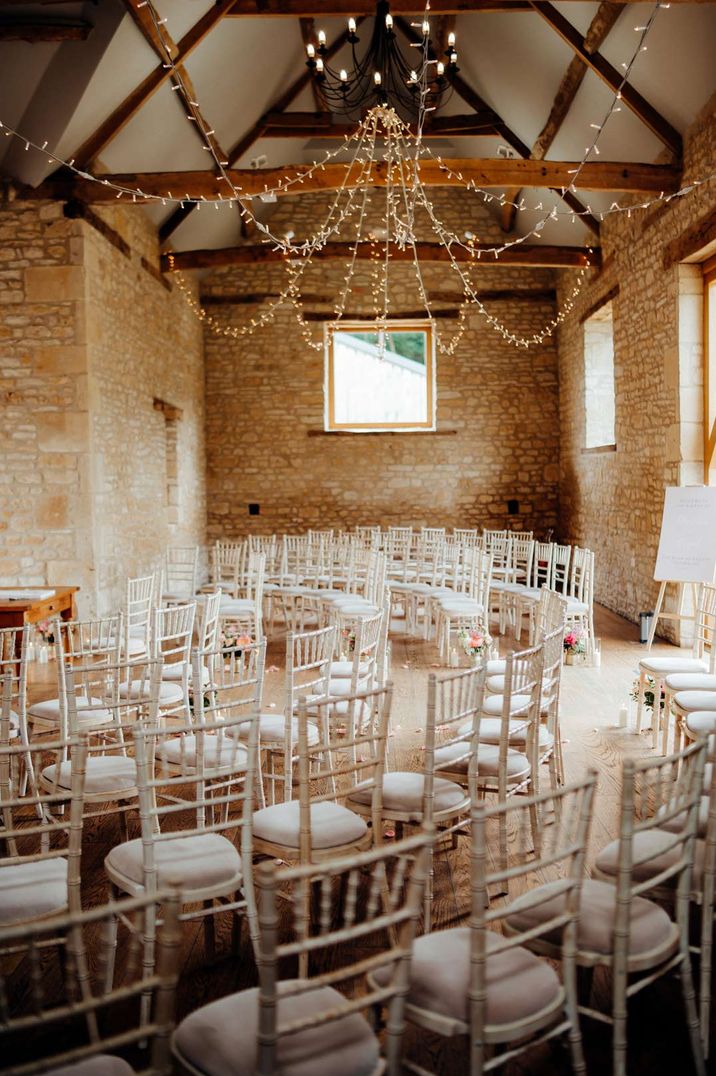 Reception room at The Barn At Upcote with fairy light details and white chairs