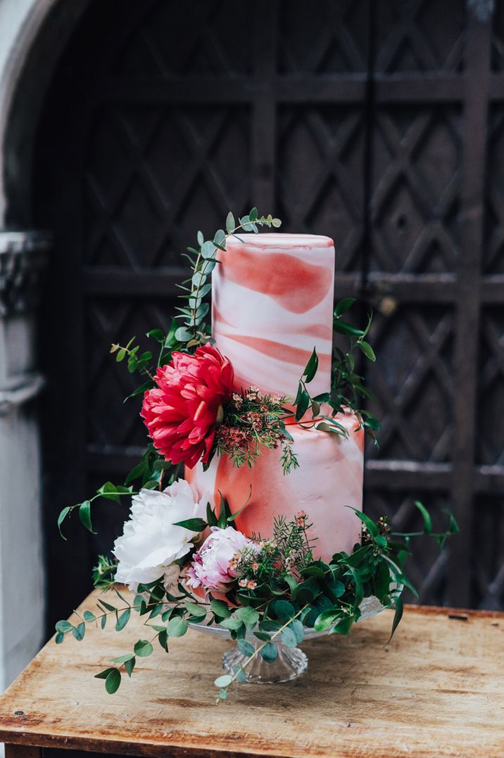 Pink and red marble effect iced two tier wedding cake with flower decor 