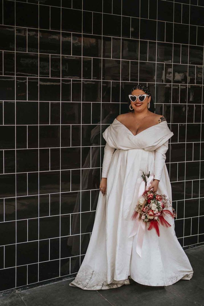 Bride in off shoulder satin look long sleeve wedding dress with heart shaped sunglasses - how far in advance should I get my wedding dress 