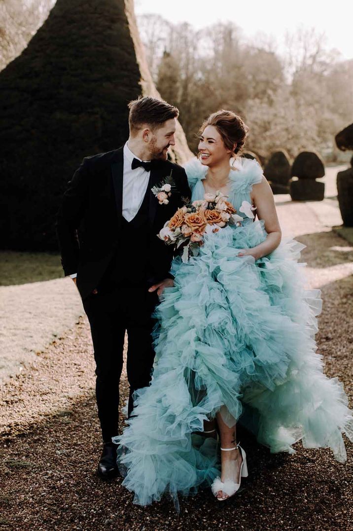 Bride in light blue tulle wedding dress holding garden rose bridal bouquet and wearing white tulle bow open toe wedding heels