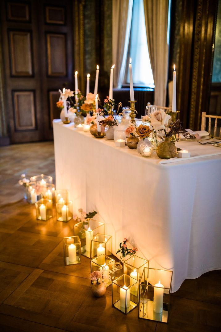 Warm twinkling candlelight surrounding table for bride and groom with modern seating arrangements 