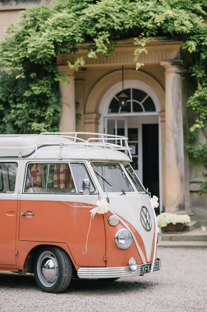 Classic VW camper van in orange and white with white ribbons and decorations