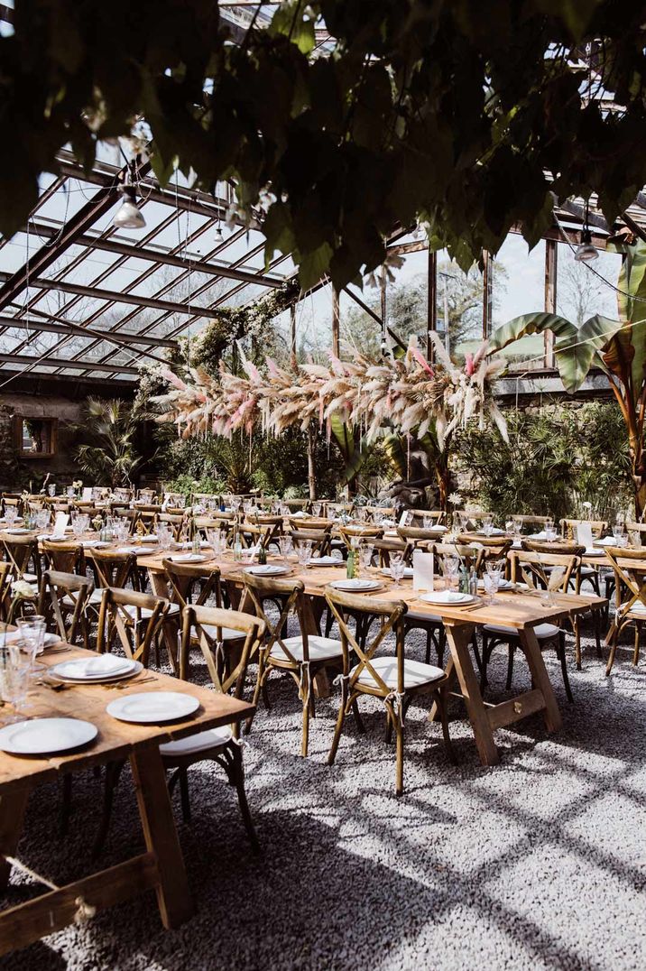 Suspended pampas grass and foliage wedding decor over neutral rustic wedding tablescapes at Anran, Devon glasshouse wedding venue 