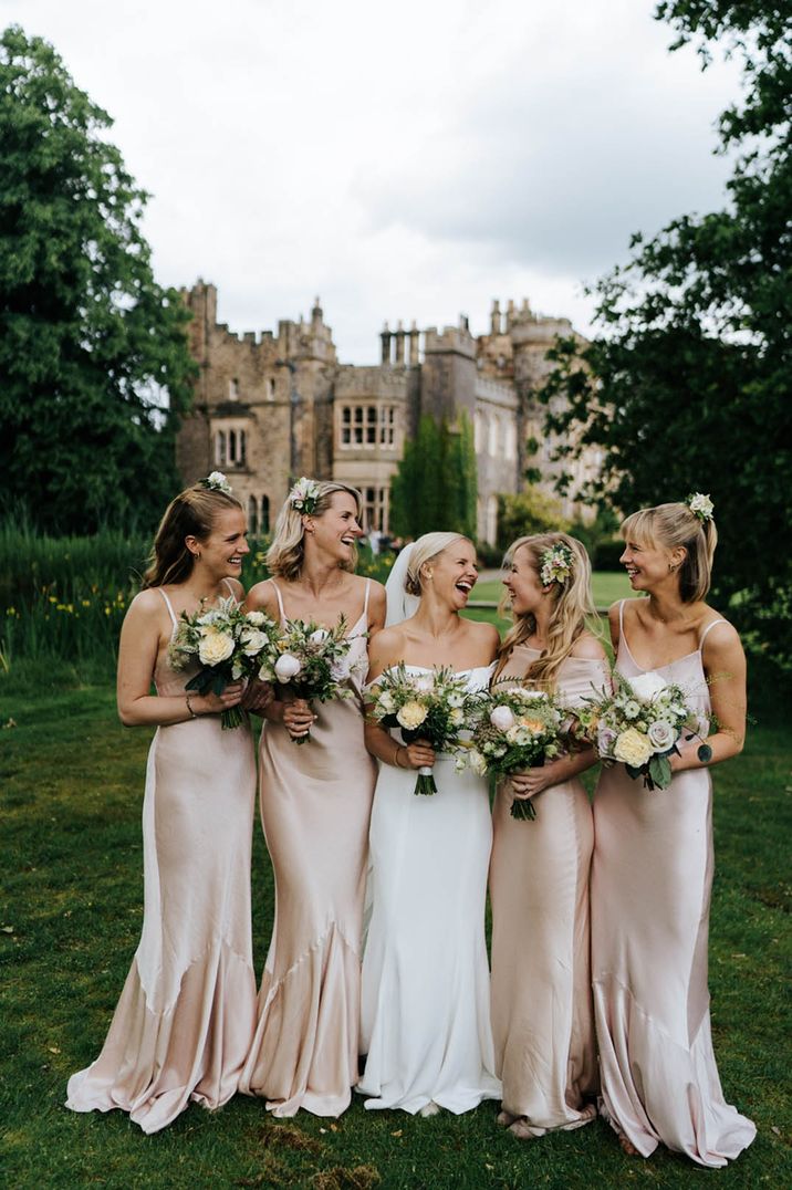 Bridesmaids in pink satin dresses with the bride in a strapless satin slip dress for wedding 