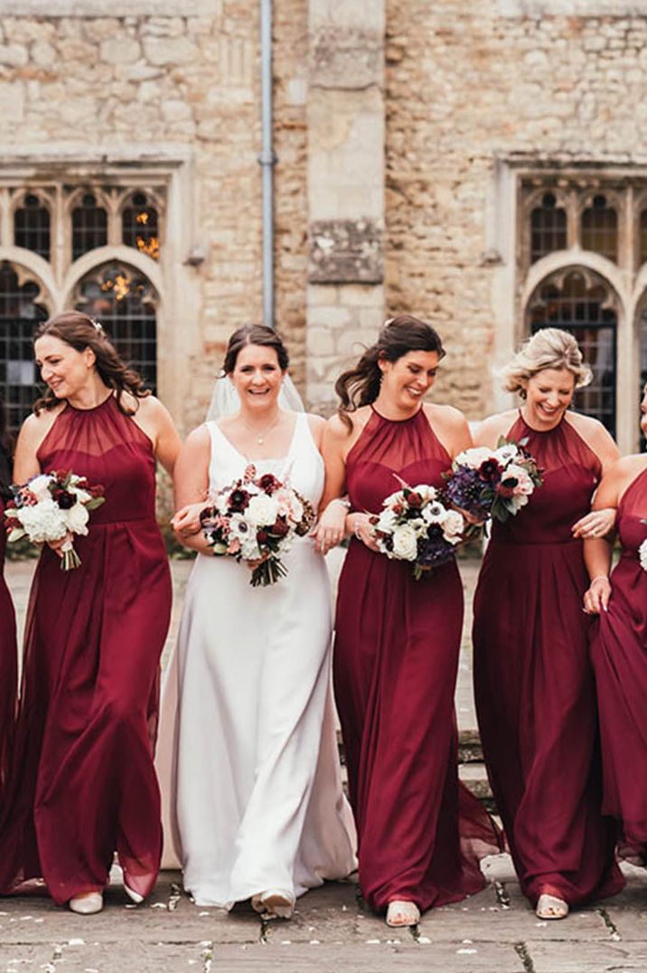 Bridal party with the bridesmaids wearing red bridesmaid dresses and the bride wearing a lace gown at Notley Abbey 