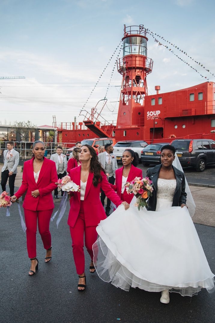 Bride in white dress with black leather jacket, bridesmaids in pink suits