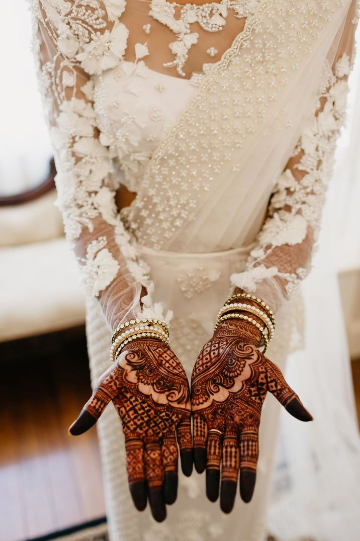 Indian bride in a white saree with henna and bangles wedding jewellery 