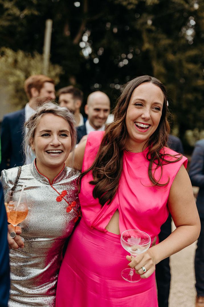 Wedding guests smiling and embracing wearing pink and silver dresses