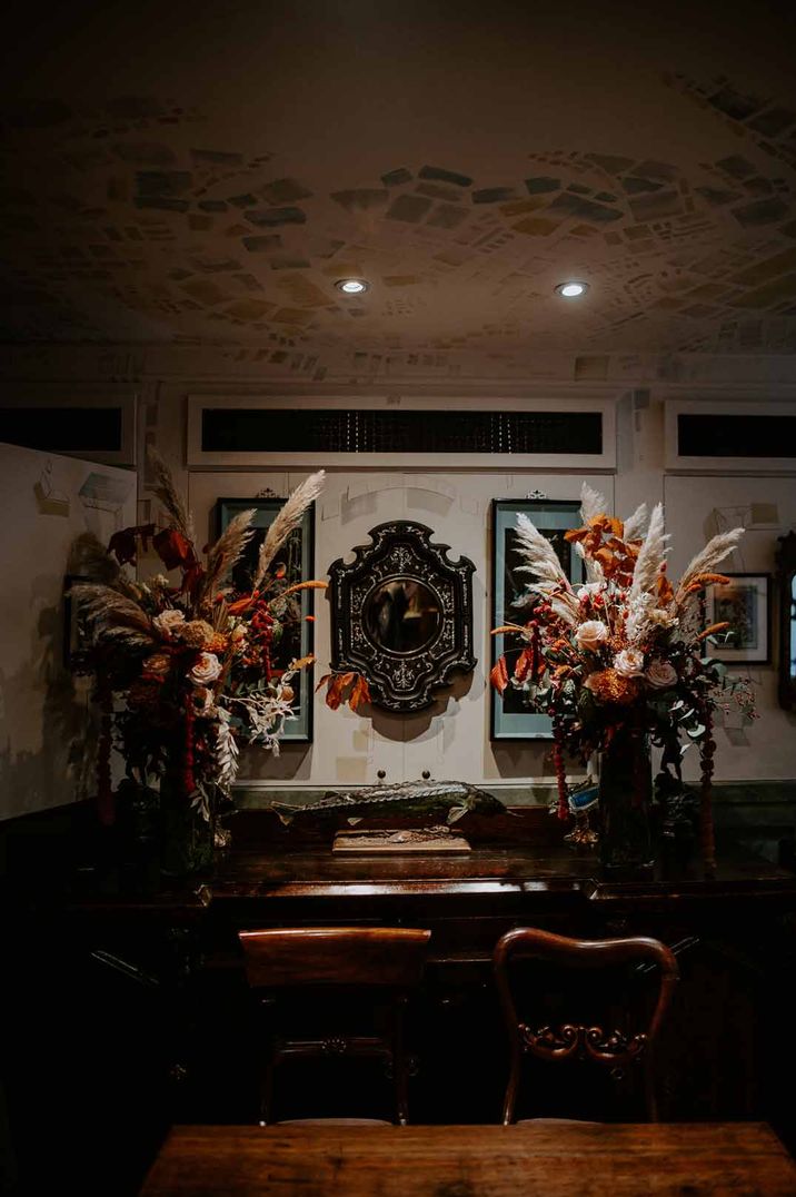 Reception room of The Zetter Townhouse London wedding venue - large dried flower and pampas grass displays, leather arm chairs and large plaques 