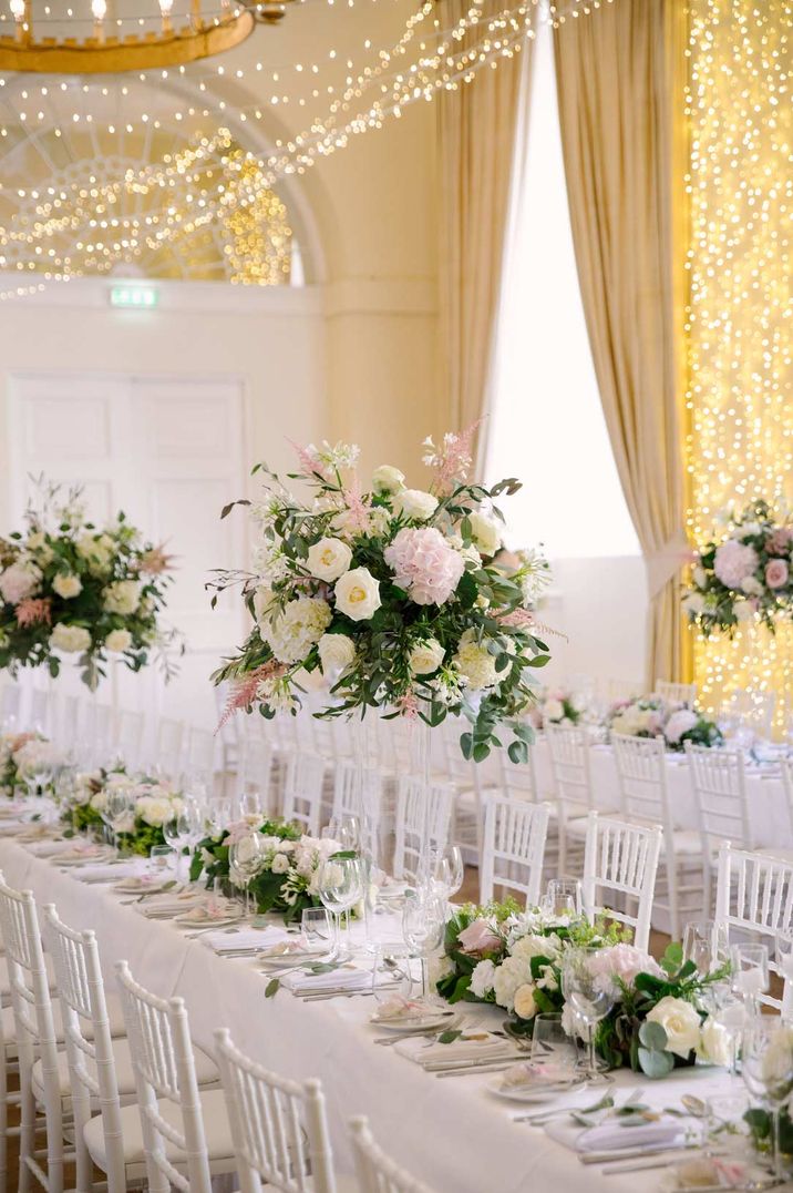 Classic wedding tablescape at Farnham Castle wedding venue with white tablecloth, garden rose peony foliage and dried flower wedding table centrepieces and table runners, fairy lights and festoon lighting 