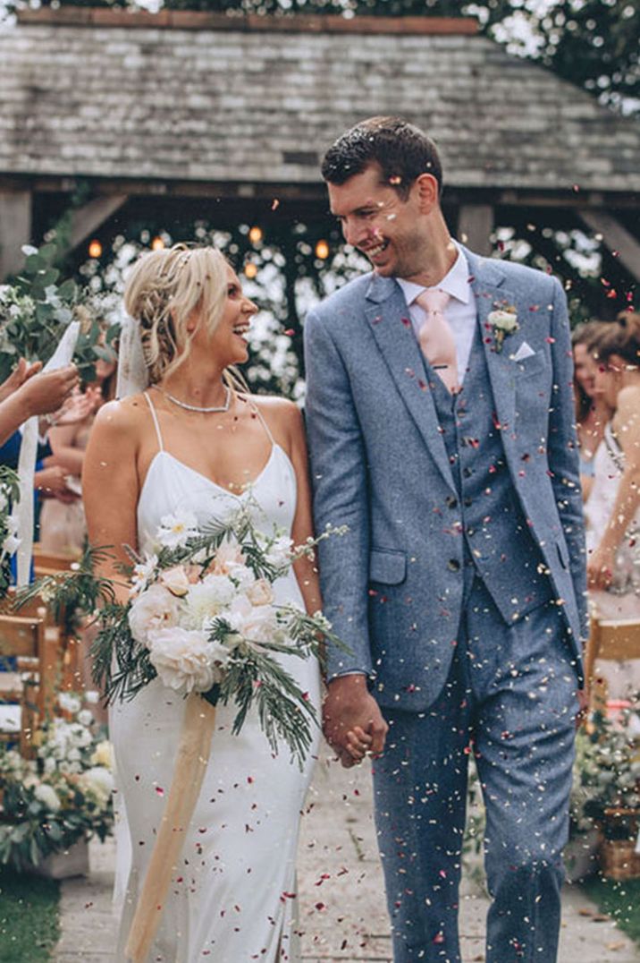 Bride in white gown with groom in light blue suit having confetti momemnt