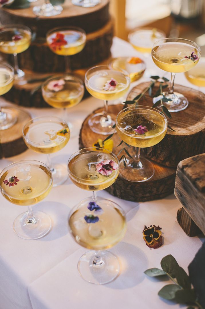 Coupe glasses of champagne decorated with edible flower garnishes 