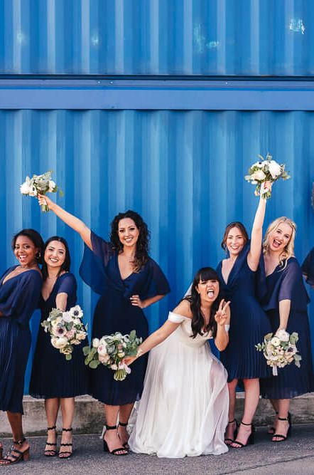 Bridesmaids wearing short pleated chiffon navy bridesmaid dresses with draped sleeves, holding white bouquets | ASOS Dresses | Kirsty Mackenzie Photography