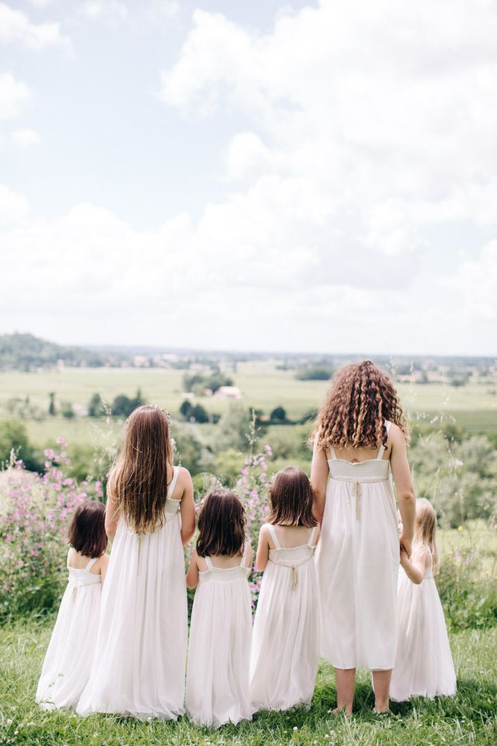 Group of young bridesmaids wearing white bridesmaid dresses, looking out into the distance