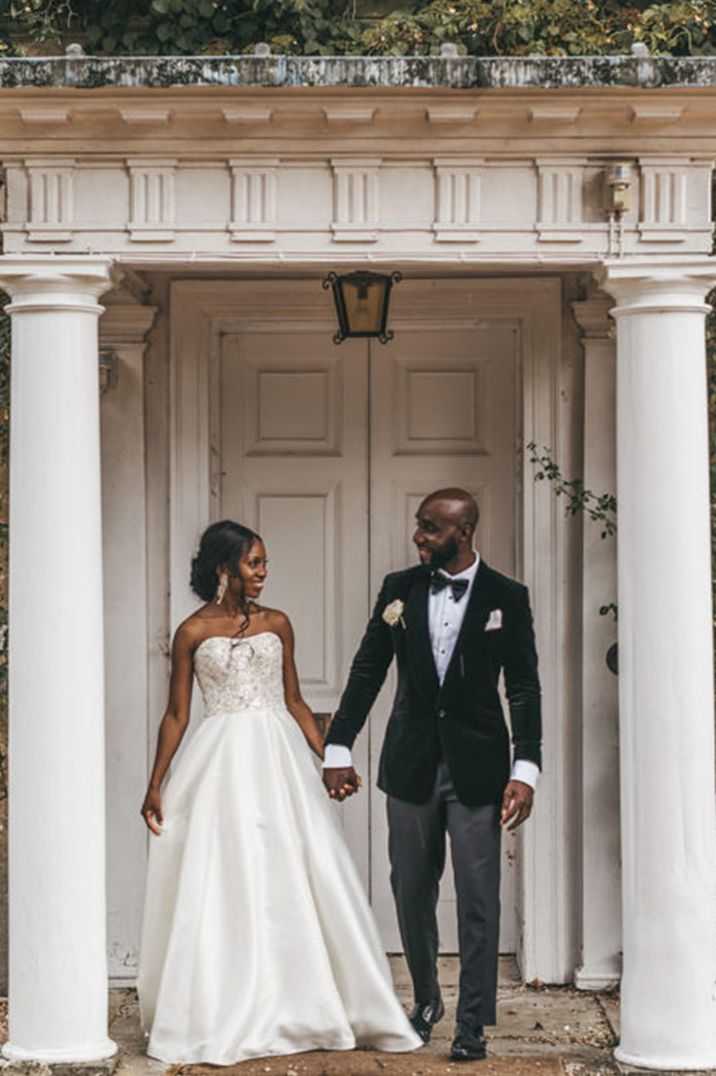 Black bride and groom pose together for their luxury classic and traditional wedding with the bride in an embellished strapless wedding dress 