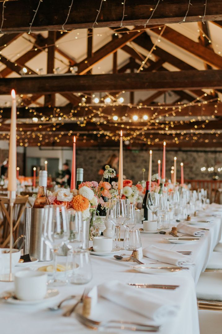 Pink and peach taper candles on rustic tablescape with fairy lights at The Wool Tower 