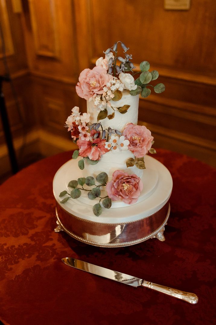 Two tier white iced wedding cake with colourful flowers 