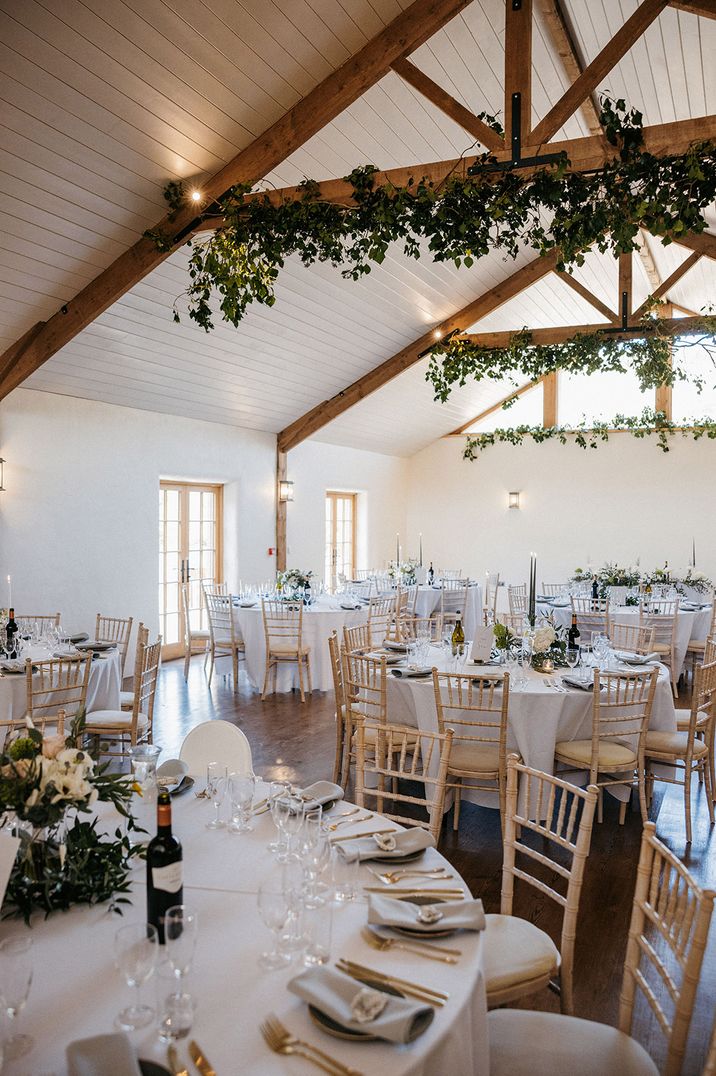 Barn wedding breakfast space with foliage to complement the rustic venue