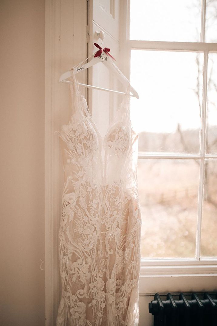 Lace wedding dresses hanging on white wooden personalised hanger by Adam Bird Photography