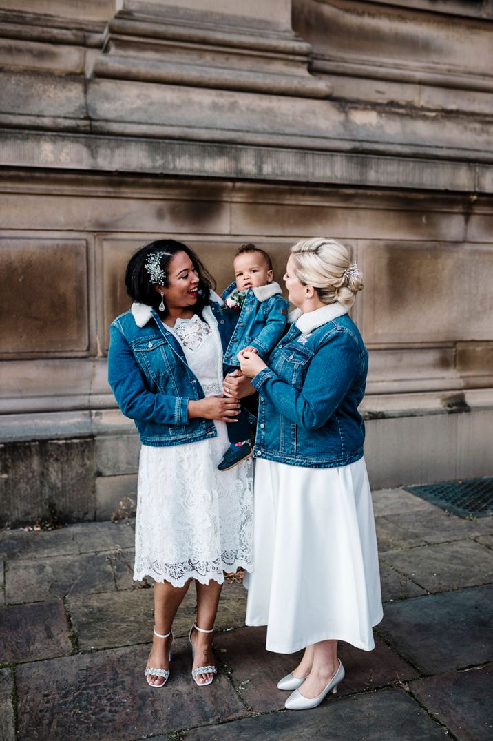 Two brides in matching denim jackets with their little boy at their wedding 