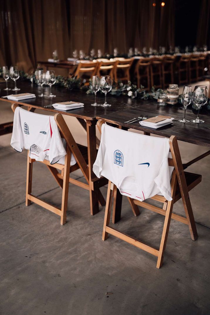 Football T shirts on the back of chairs at wedding reception used as memorable decorations at DIY wedding