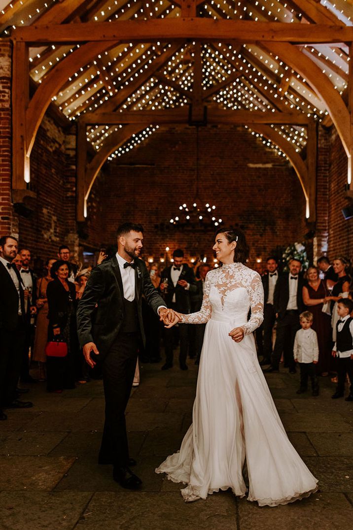 The bride and groom have their first dance together at the Hazel Gap Barn with fairy lights and white drapery 