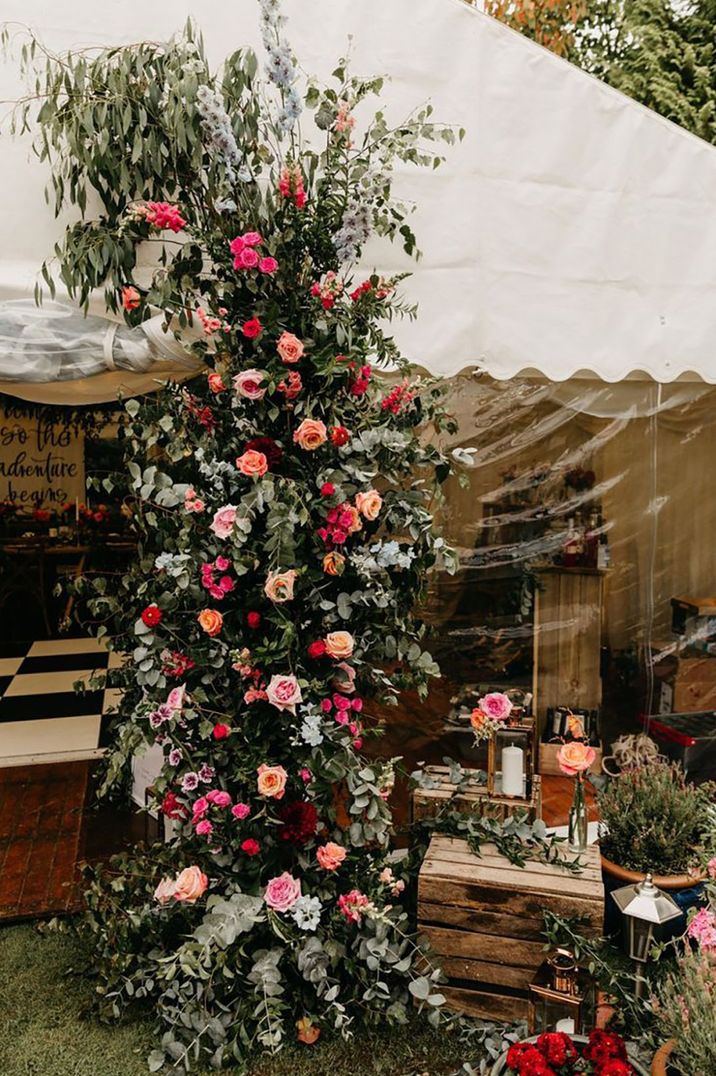 Flower column made with pink and orange wedding flowers decorating the entrance to the marquee 