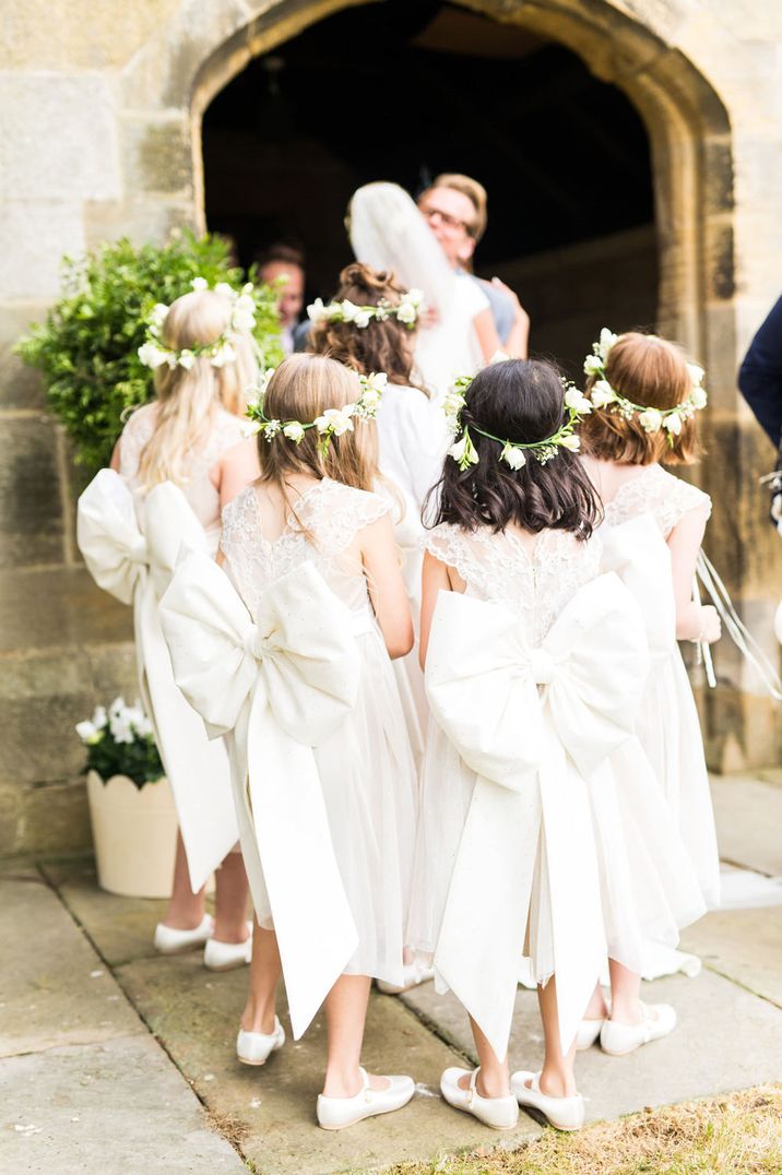 Flower girl entourage in traditional ivory dresses with giant bow back detail 