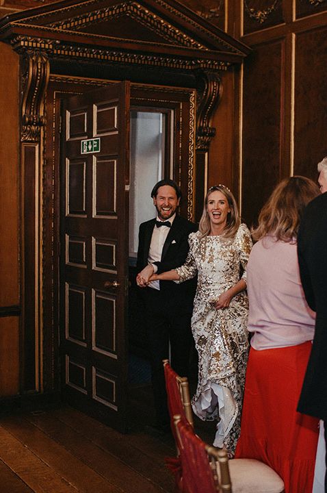 Bride in sequin Abigail Gardenia evening gown and groom in tux entering hall