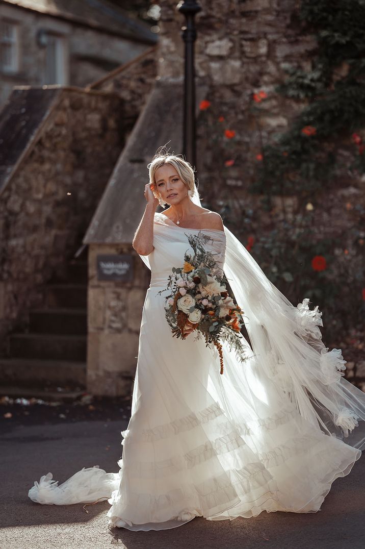 Bride in off the shoulder tulle layered wedding dress with embroidered veil and large bridal bouquet 