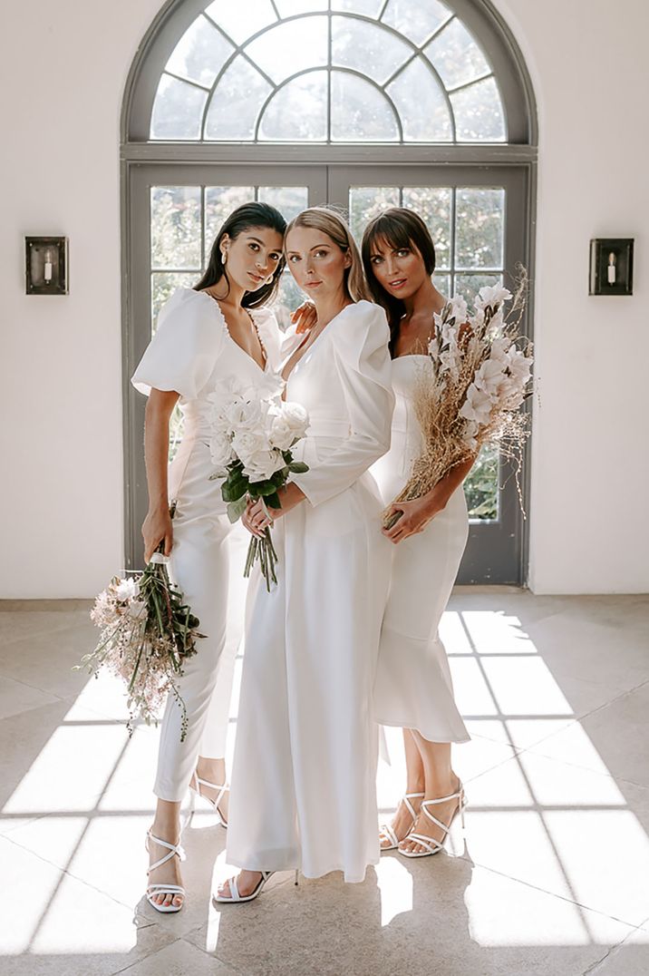 Classic and traditional country house wedding with bride and bridesmaids in white outfits with white bouquets 