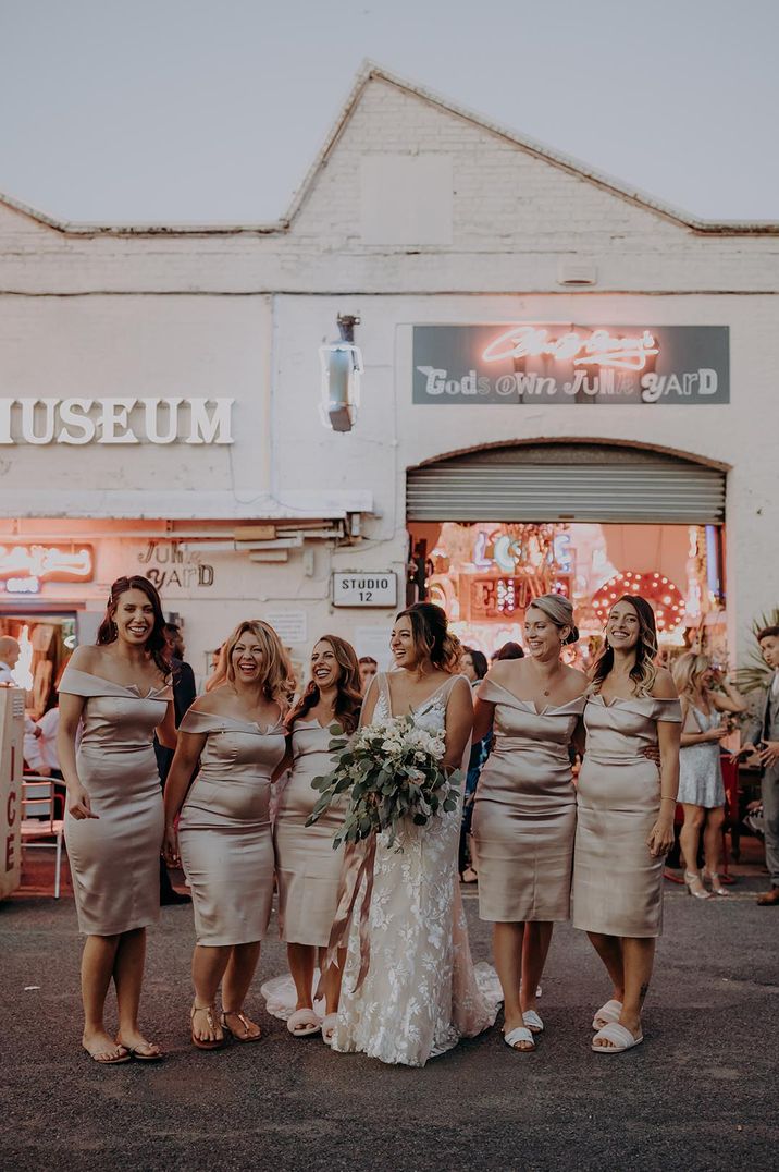 Bridesmaids in off the shoulder fitted gold midi bridesmaid dresses for modern city wedding 