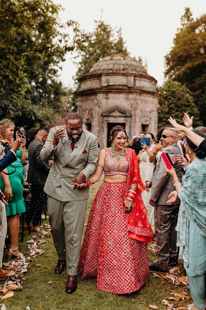 Larmer Tree Gardens outdoor wedding ceremony colourful confetti moment as the bride and groom walk back down the aisle as a married couple